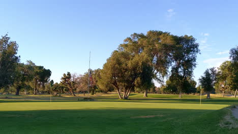 bandera estadounidense a media asta en un campo de golf en un día claro y soleado