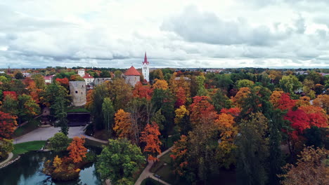 aerial view of cēsis castle, one of the most iconic and best preserved medieval castle in latvia with autumnal forest surrounding the fortress on a cloudy day