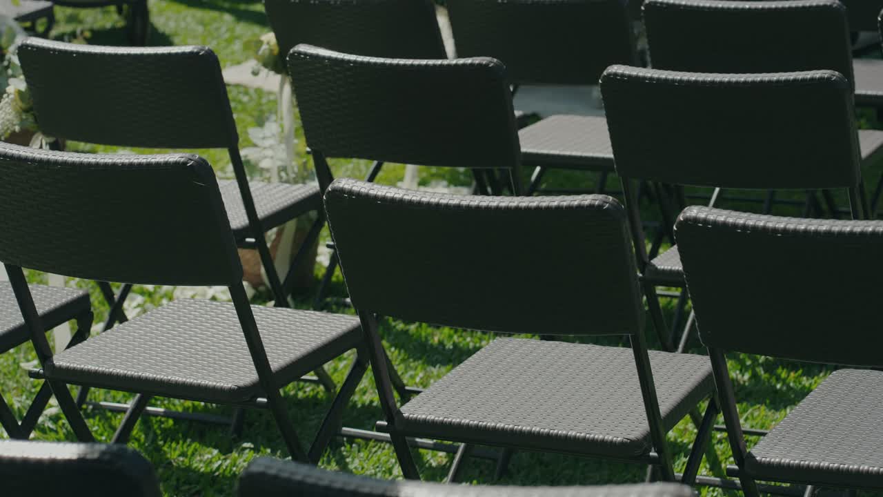 Empty black chairs set up outdoors for ceremony or event