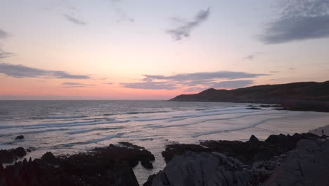 waves crashing against a sandy beach at dusk during summer