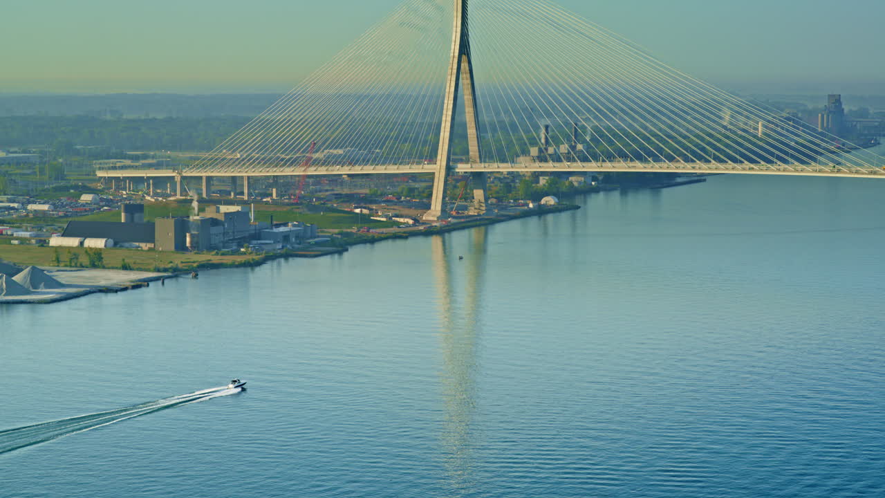 Drone shot showing a boat moving down the Detroit River beneath the Gordie Howe Bridge