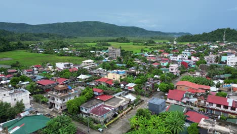 establishing, aerial view of quaint barangay village with island meadows and mountains in background