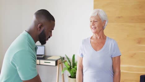 video of happy african american male physiotherapist examining caucasian senior woman