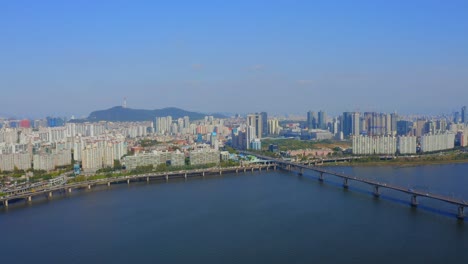 화창한 날 서울의 주거 지역과 다리를 향해 한강 위로 앞으로 이동하는 드론 샷