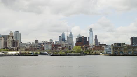 Horizonte-De-Filadelfia-Sobre-El-Tranquilo-Río-Delaware-En-Un-Día-Cálido-Y-Nublado-Con-Algo-De-Tráfico-En-Las-Carreteras