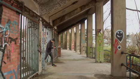 urban explorer man walks through decrepit stadium ruins with graffiti, static