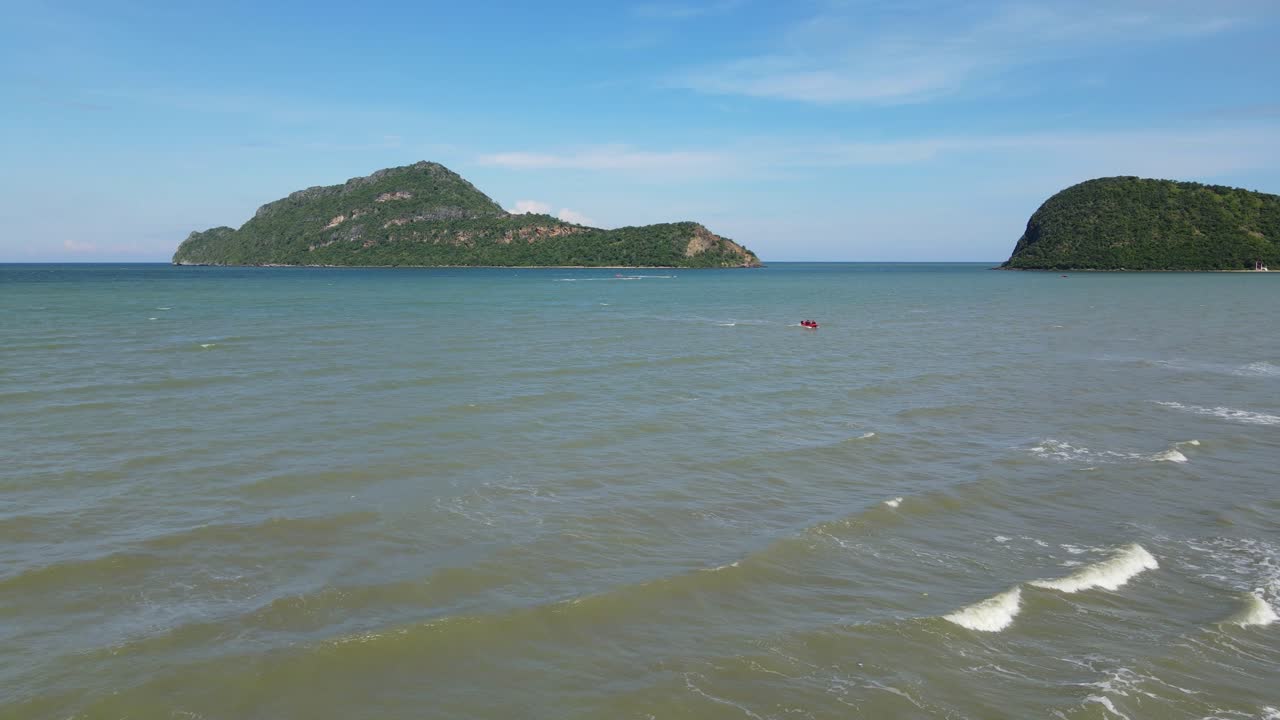 해안으로 향하는 빨간색 쾌속정, 밀려드는 파도, 유혹하는 섬의 꾸준한 공중 영상