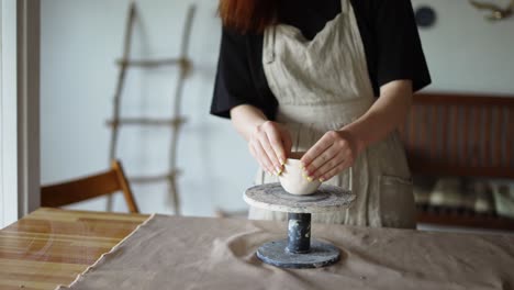 girl potter forms her product and turns the potter's wheel