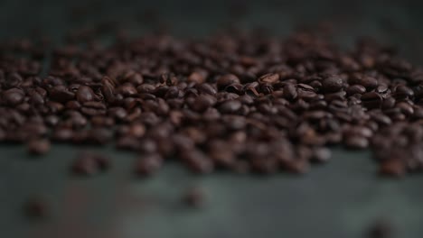 granos de café de primer plano cayendo, derramándose sobre la mesa oscura