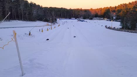 Gente-Divirtiéndose-Haciendo-Tubing-De-Invierno-Cuesta-Abajo-En-El-Parque-De-Tubing-De-Nashoba,-Massachusetts