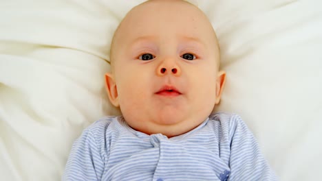 Baby-boy-smiling-while-relaxing-on-baby-bed-4k