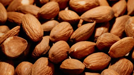 close up of a big pile of almonds on a wooden table tilting from top down to side in studio lighting