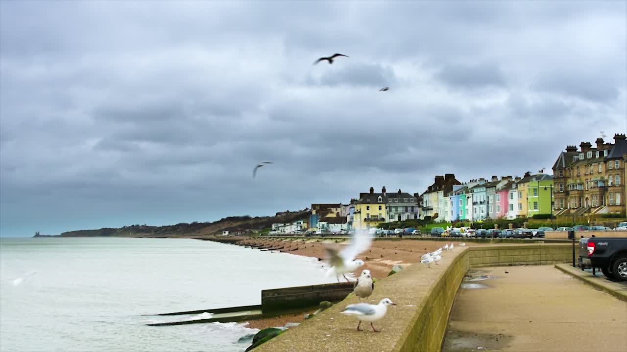 nubes tormentosas y gaviotas se reúnen mientras el viento sopla sobre la pintoresca ciudad costera inglesa de herne bay, con una vista clásica a lo largo de las casas adosadas frente al mar y la playa de guijarros