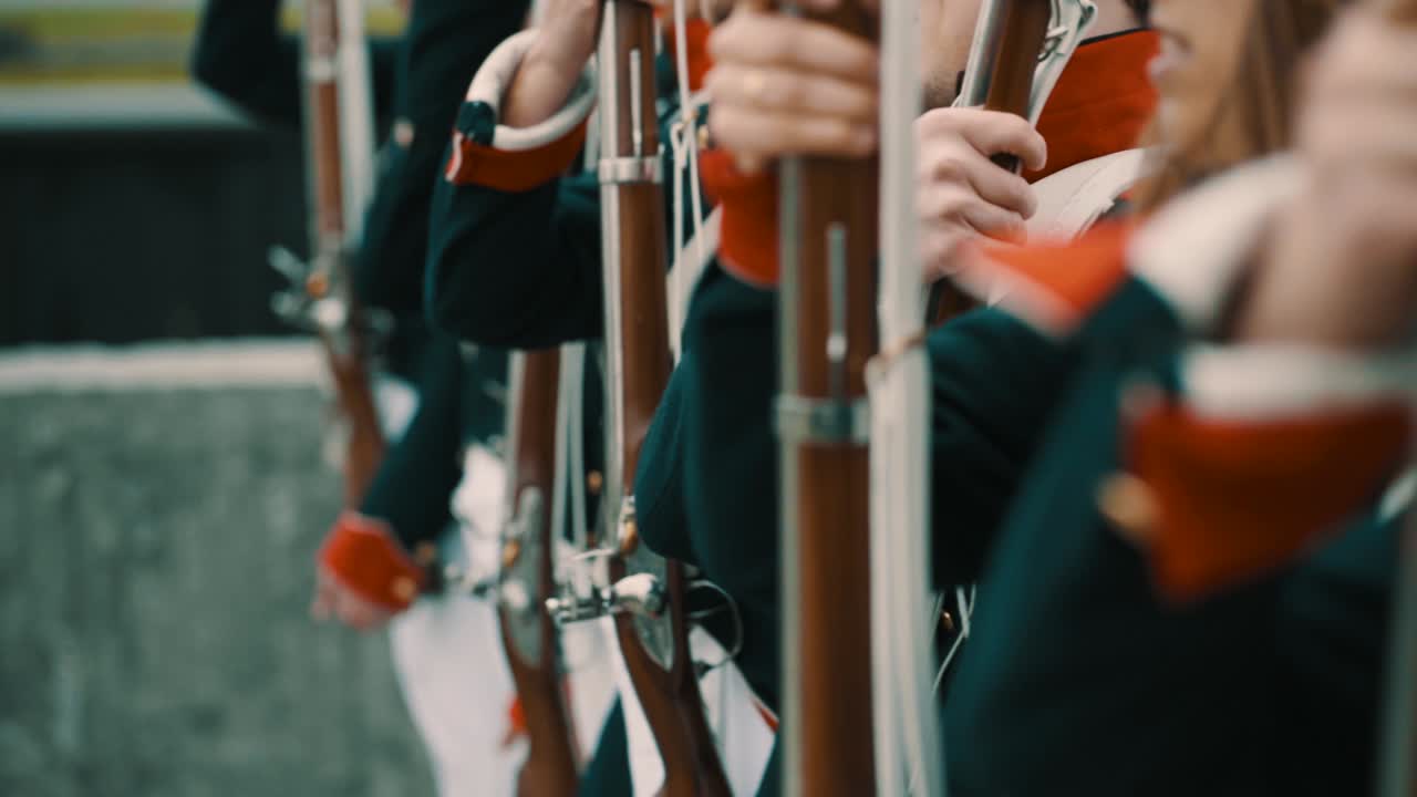 Group of French historical soldiers picking up and showing their rifle simultaneously in slow motion.