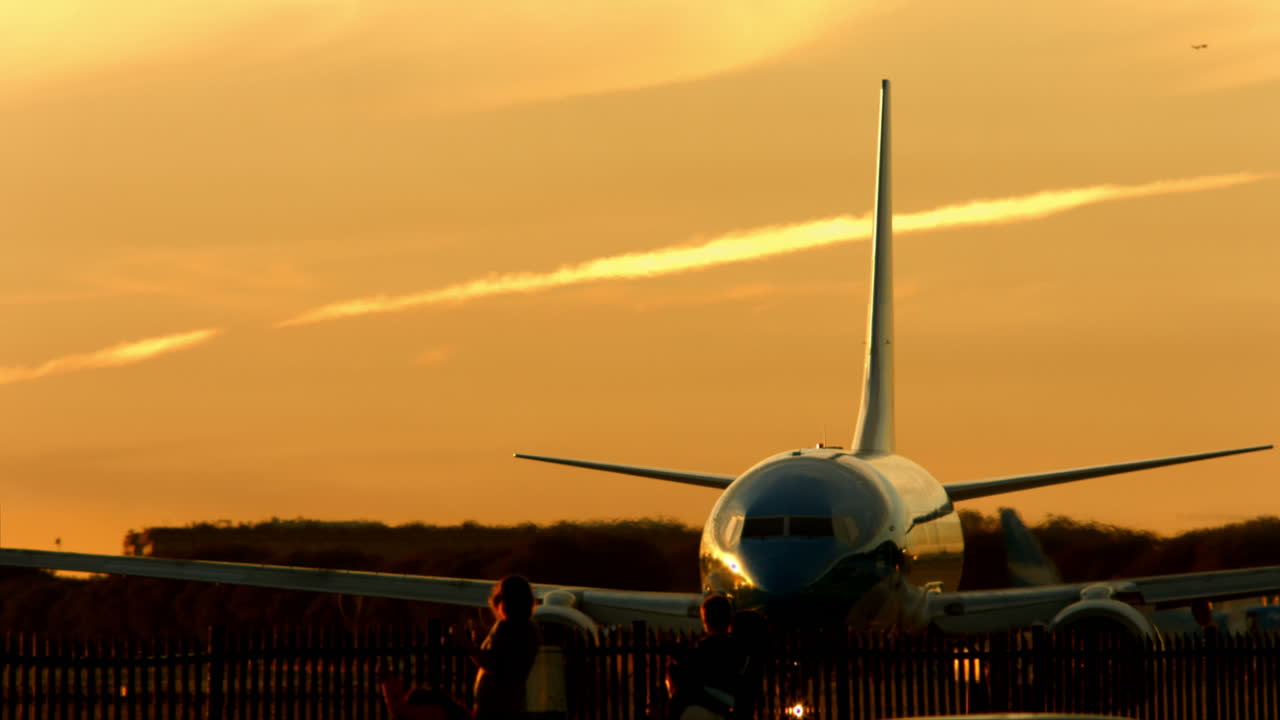 Grande Avião de Passageiros no Pátio Durante Pôr do Sol Dourado com Pessoas Observando