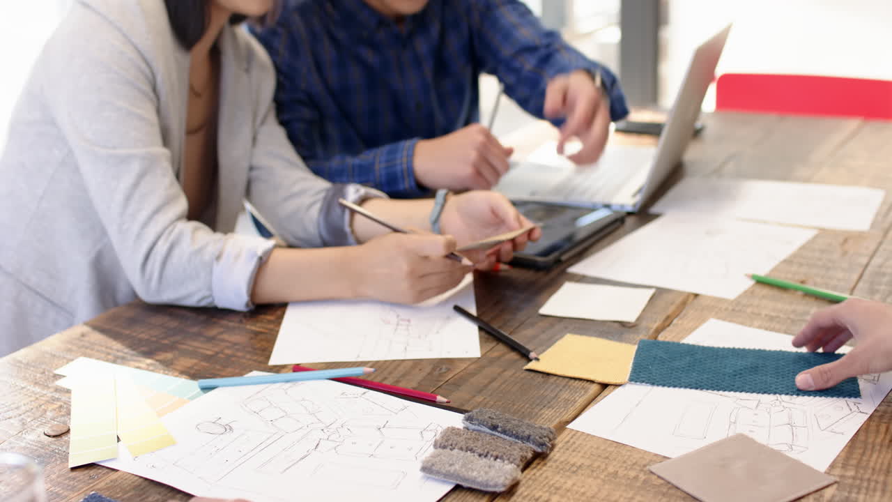 Reviewing sketches and materials, two people collaborating on interior design project, at office