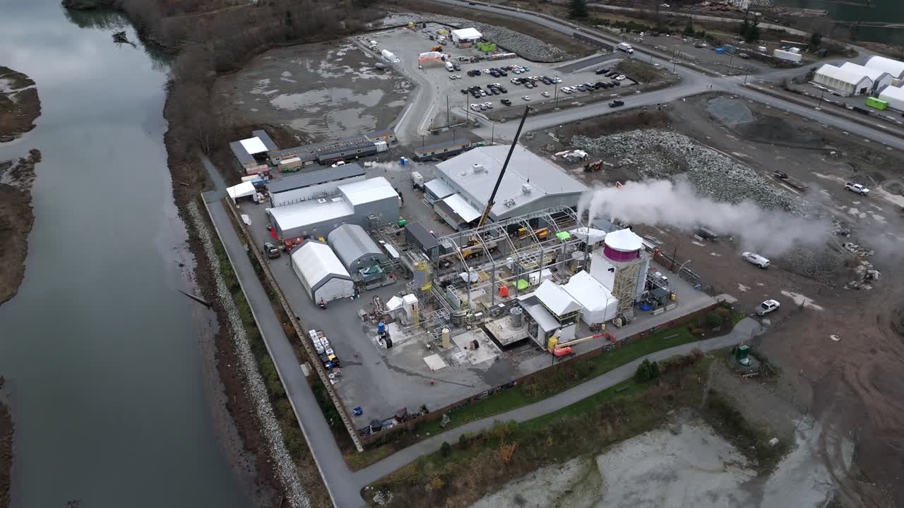 Squamish, Canada – Et industrianlegg ligger ved vannet, med bygninger, maskineri og damp som stiger opp fra aktiv drift – Orbit drone shot
