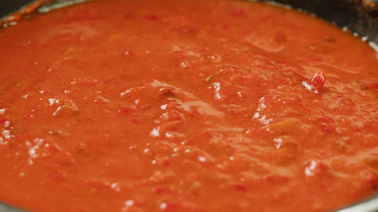 Boiling tomato sauce on a frying pan close-up. Cooking tomato sauce or soup. Traditional Italian Mexican Asian dish. High quality studio shot for cafe, restaurant close up. Marinara sauce for Italian pasta
