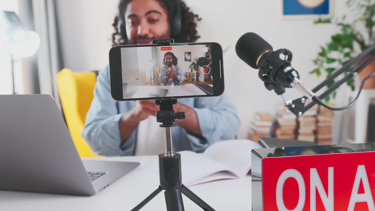 joven admirando a un hombre árabe videoblogger aplaude grabando video en el teléfono