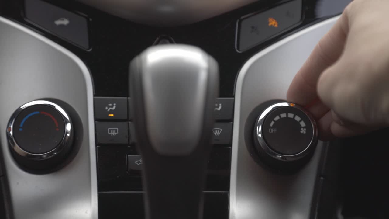 Driver's Hand Turning Off The Car Temperature Knob Near The Center Console - close up
