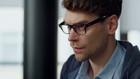 Focused businessman looking screen in glasses closeup. Thoughtful man solving