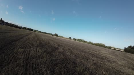 fpv drone encima de tierras de cultivo agrícola pasando por campo tree hedge uk
