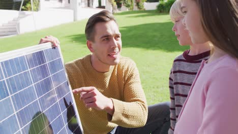 Video-Eines-Glücklichen-Kaukasischen-Vaters,-Der-Seinem-Sohn-Und-Seiner-Tochter-Im-Sonnigen-Garten-Das-Solarpanel-Erklärt