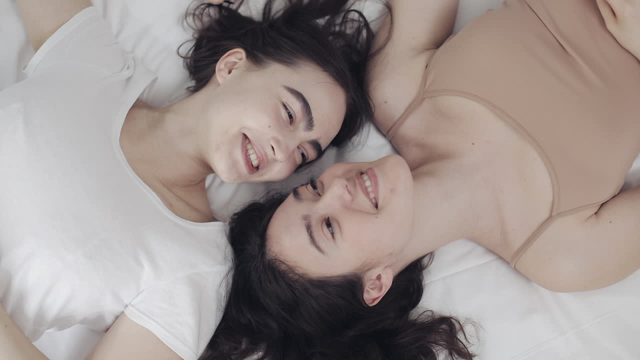Due donne sorridenti sdraiate a letto