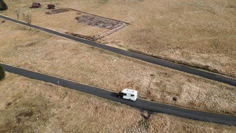 Aerial-view-of-a-lone-caravan-driving-along-a-winding-mountain-road