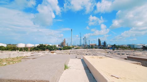 low angle shot from within an empty cemetery in curacao showing a large industrial refinery in the distance