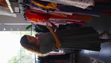 Vertical-Video-Of-Female-Owner-Or-Worker-In-Fashion-Clothing-Store-Checking-Stock-With-Digital-Tablet