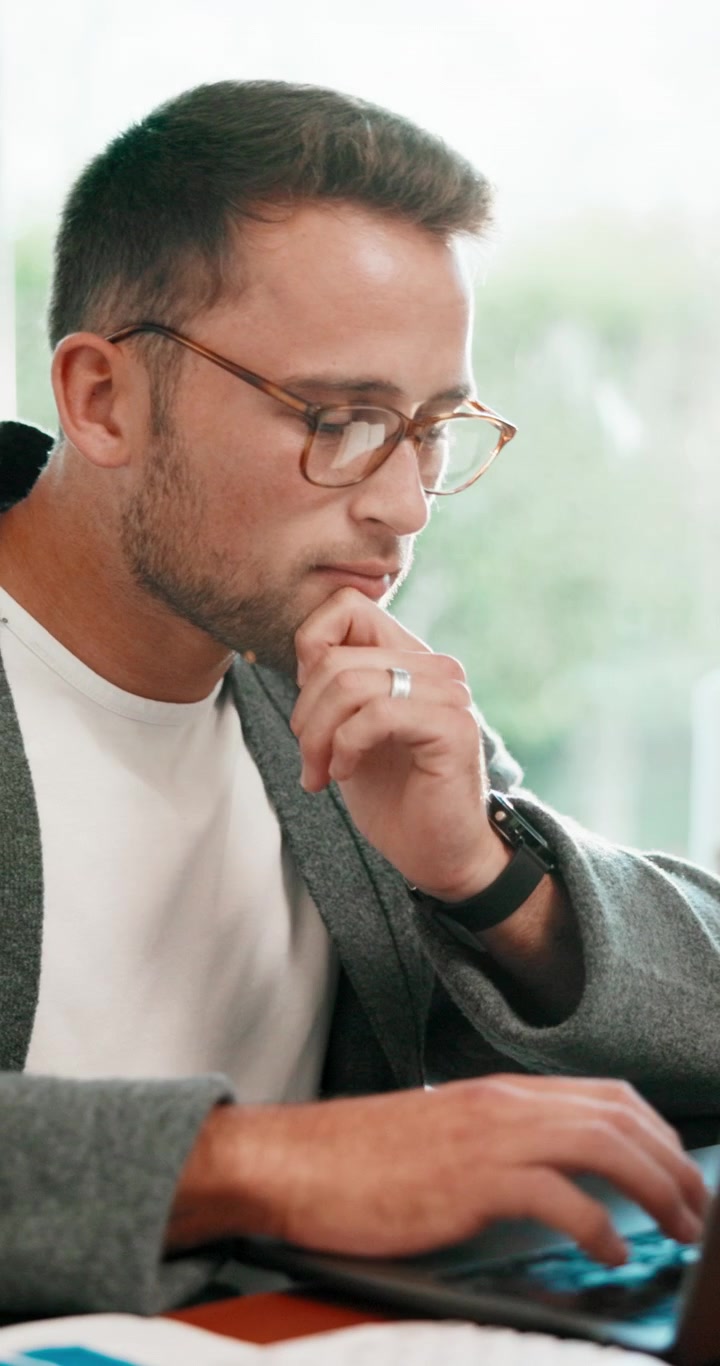 Giovane uomo concentrato mentre lavora al laptop in un ufficio luminoso