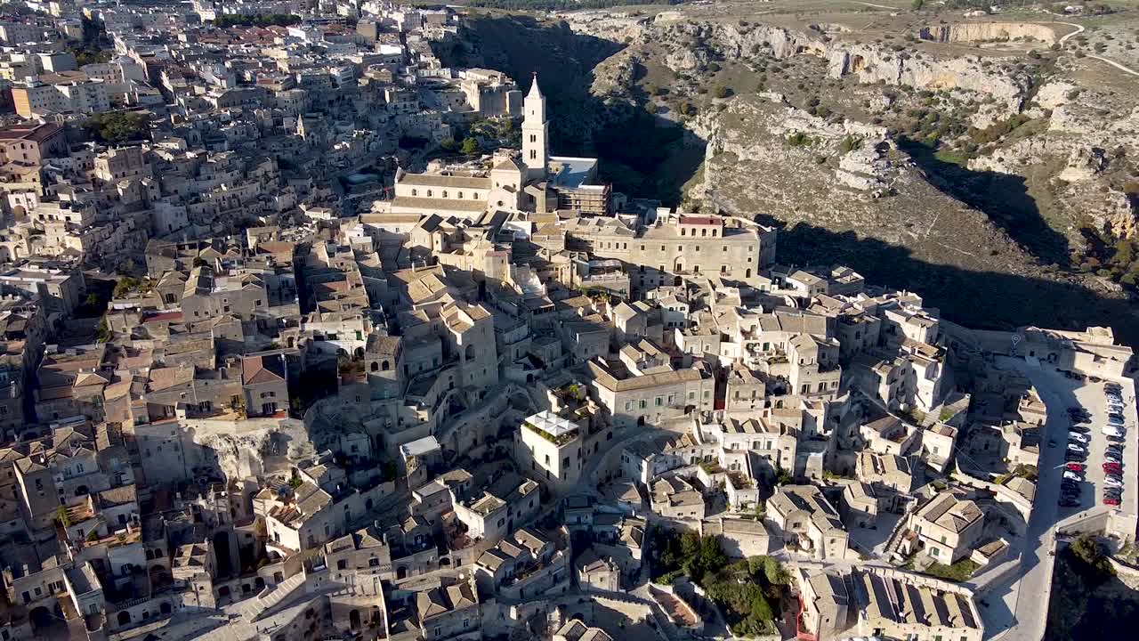 Drone zooming out from hills of ancient city Matera in Italy, church in the middle of the shot