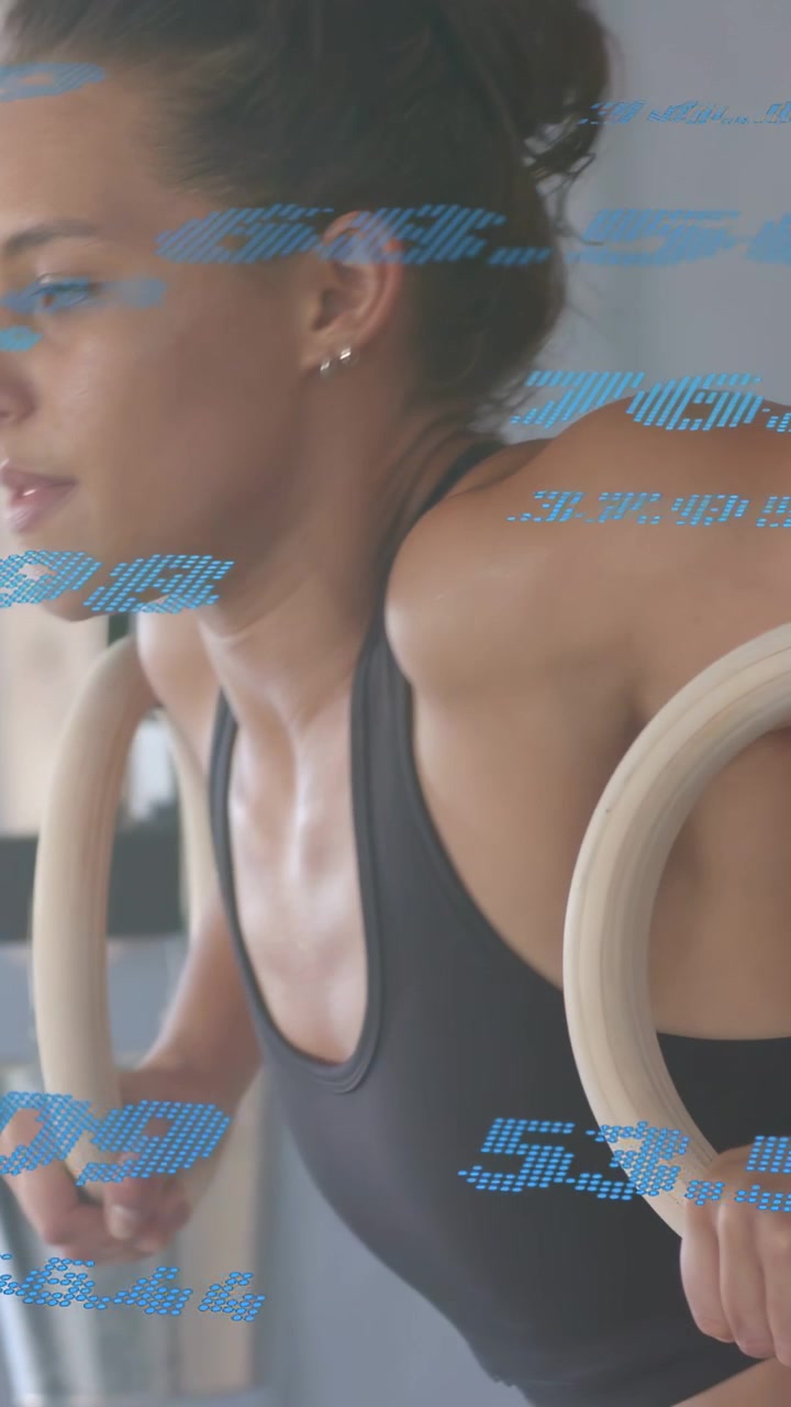 Vertical video: Woman gripping rings, lowering chest holding in gym, blue numbers tracking power
