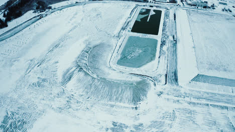 flyover of frozen water treatment reservoir covered with ice and snow