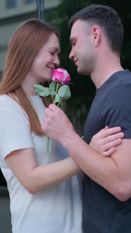 a guy gives a pink rose to a girl in a white tshirt a guy gives a pink rose to a girl in a white tshirt a couple in love