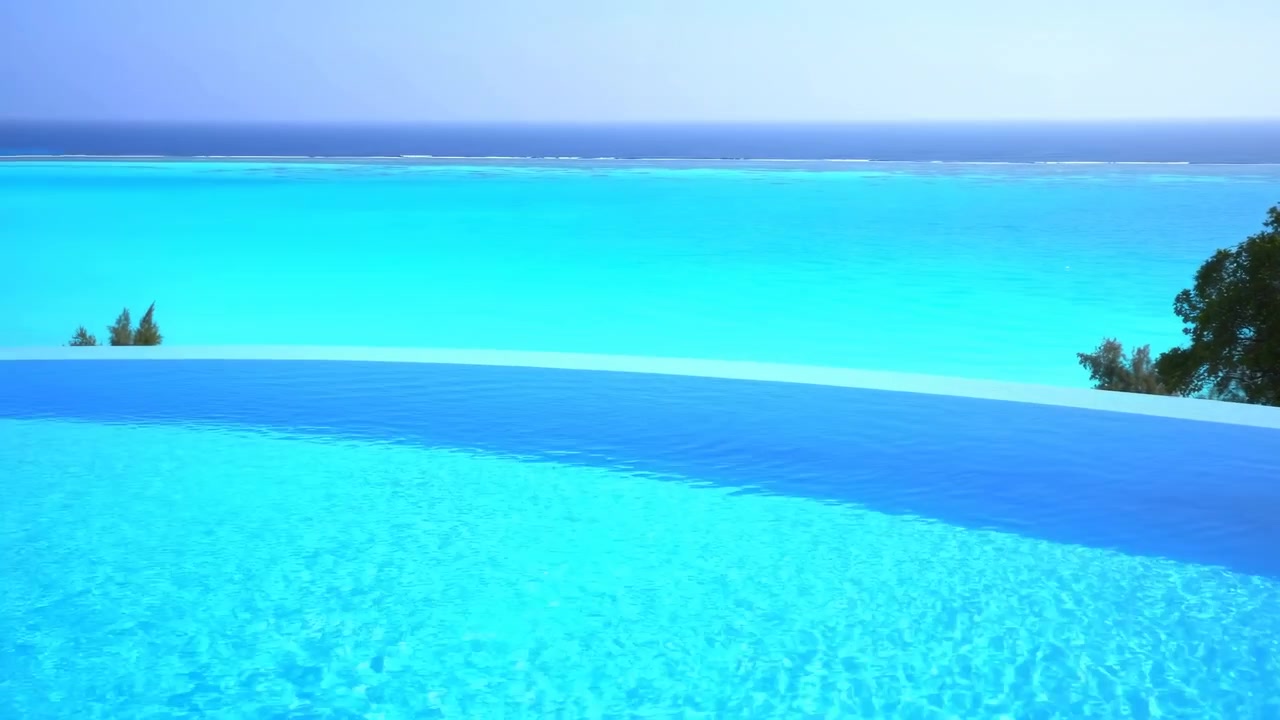 ターコイズブルーの海を見下ろすインフィニティプール、ヤシのシルエットが映える穏やかなヴィラのテラス、きらめく水面、陽光が降り注ぐ