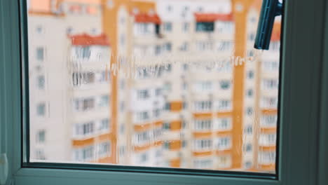 wiping window with a brush. view from flat on a plastic window cleaning with a special tool in the city. housekeeping concept.
