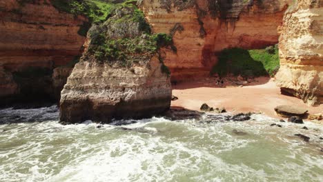 círculo aéreo de drones 4k de la bahía de playa oculta con influencers bailando y saltando en el fondo cerca de lagos, región del algarve de portugal