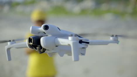 niño volando un dron en el lado de la playa