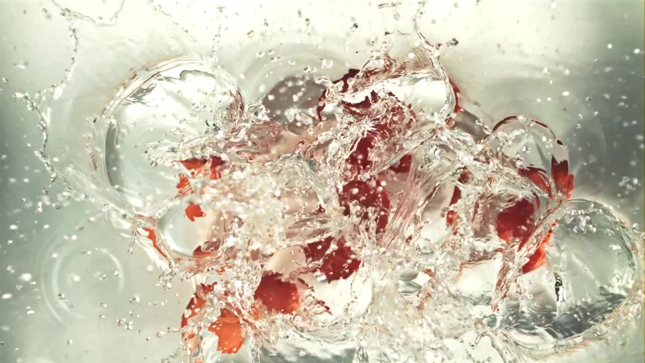 Red Cherry Tomatoes Splashing into Clear Water in Slow Motion