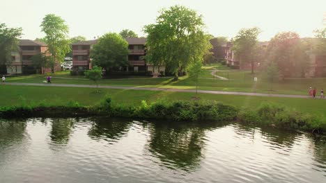 super-slow-motion-sunset-aerial-above-lake-with-unrecognisable-people-that-taking-a-walk-in-the-park