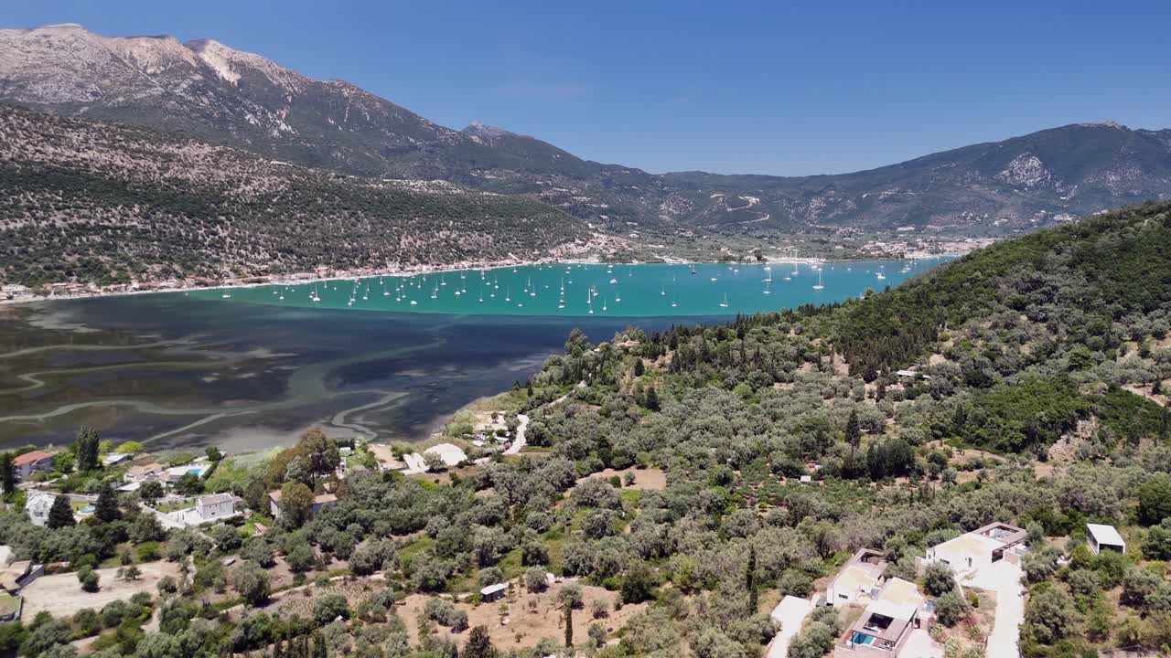 Aerial rises over hill to reveal boats in Nydri Bay on Lefkada, Greece