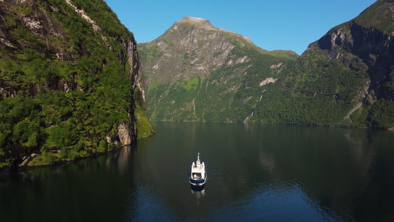 un dron vuela sobre un barco blanco en el fiordo de geiranger en una hermosa mañana de verano.