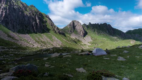 male hiker sets single-person tent for camping in mountain valley, timelapse