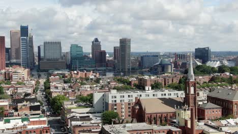 aerial parallax shot of baltimore, maryland, usa urban city neighborhood community, church steeple, united states usa downtown district skyline, inner harbor and chesapeake bay