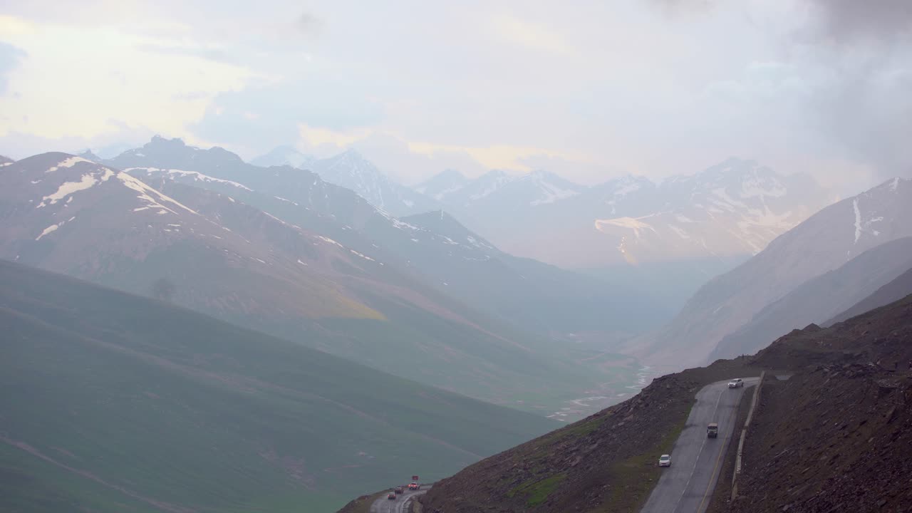 Cars Driving On A Road Through A Dramatic Mountainous Landscape In The Hunza Valley, Pakistan.