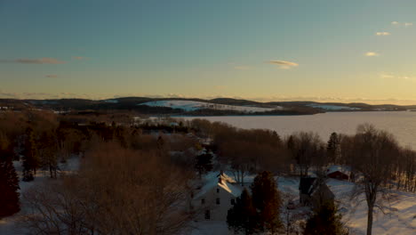 vue aérienne panoramique survolant une petite ville couverte de neige au coucher du soleil