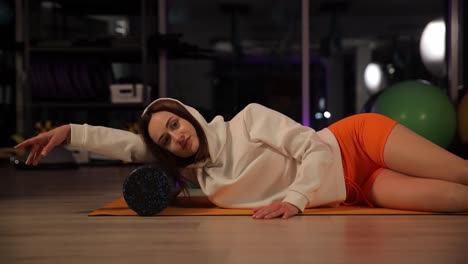 woman stretching with foam roller in gym