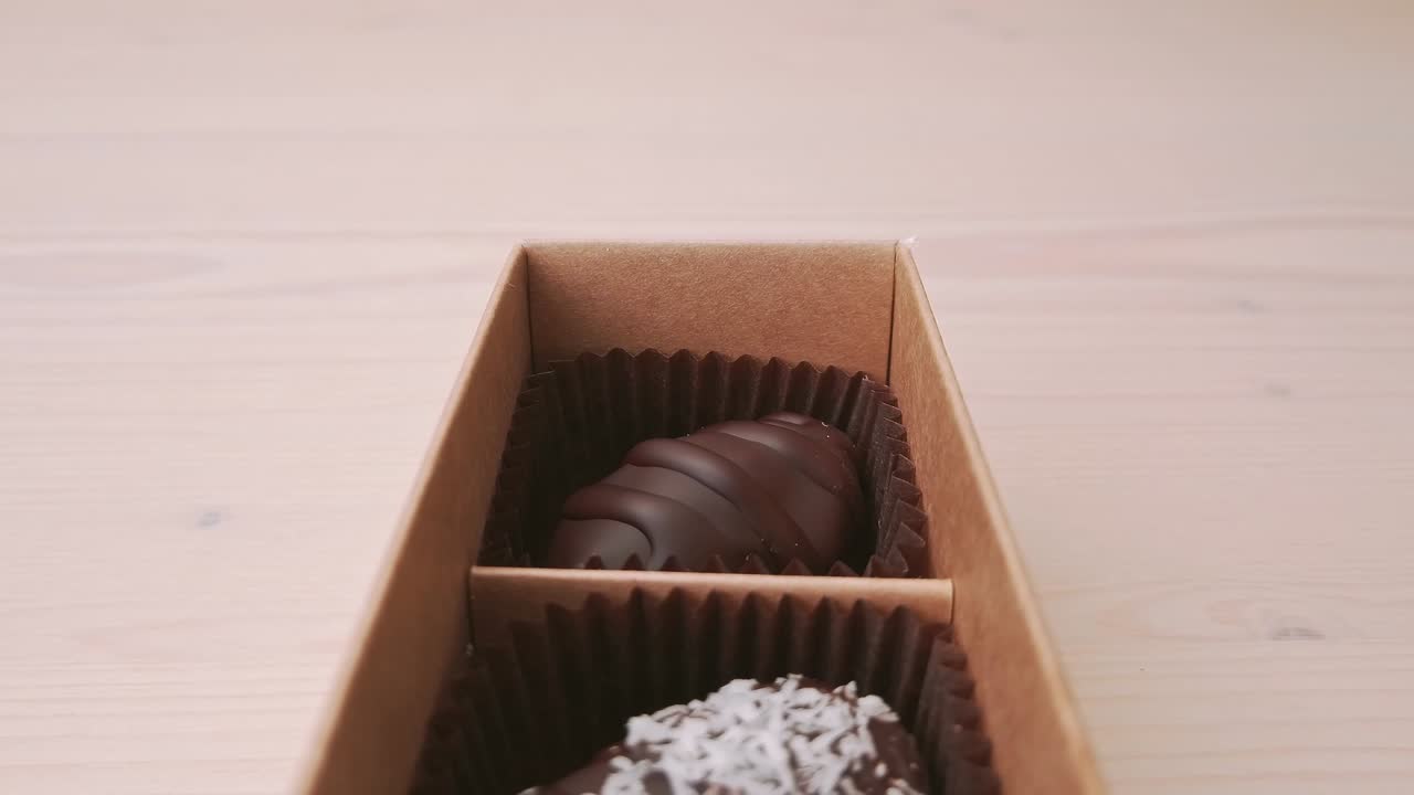 fabricación de cajas de regalos de caramelos de chocolate movimiento de cámara de primer plano extremo. chocolates variados confitería en fondo blanco cámara lenta, deslizador